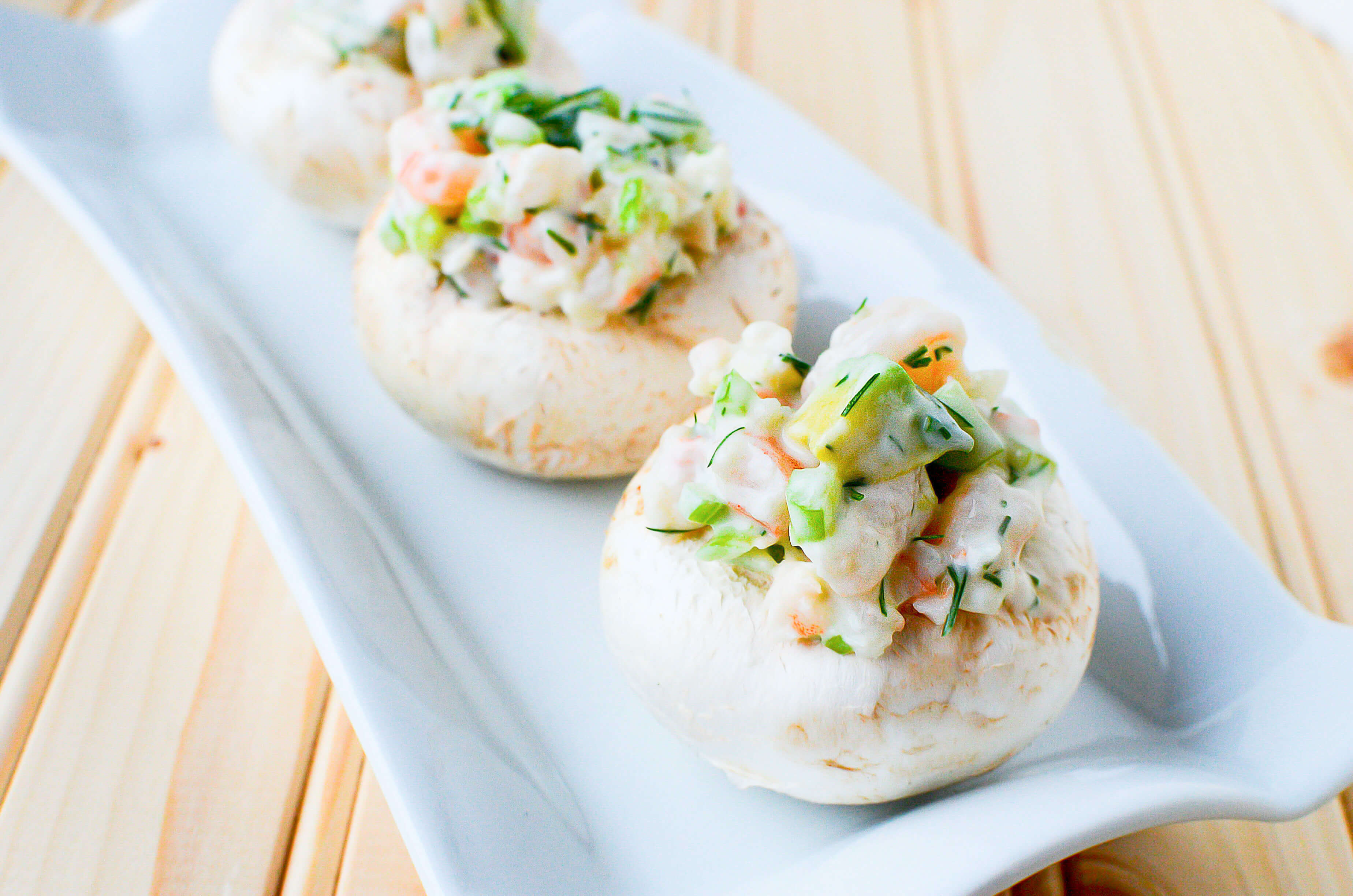 A side view of three mushroom tops filled with shrimp and avocado salad
