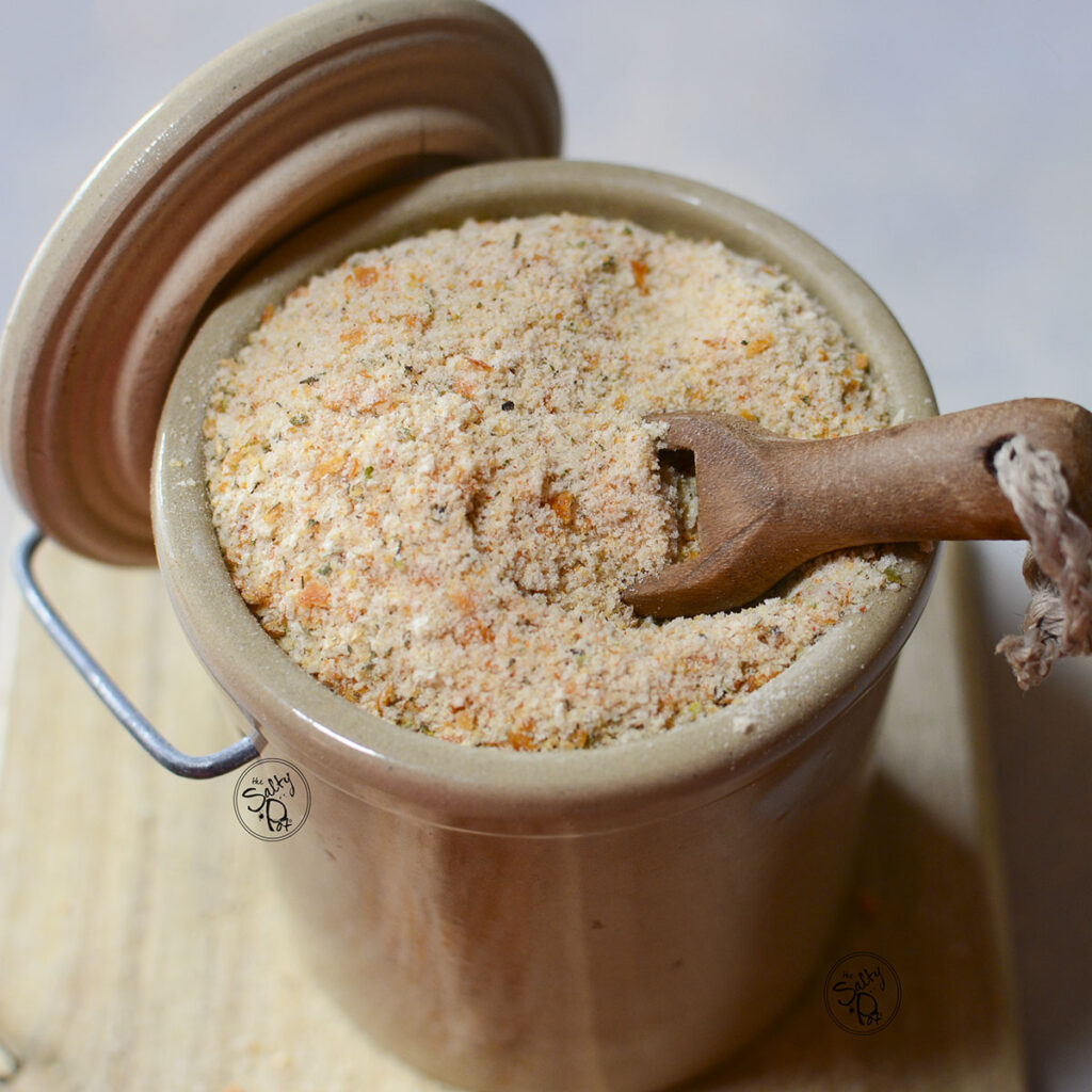 Seasoned breadcrumbs in a crock with a spoon sticking out of it.