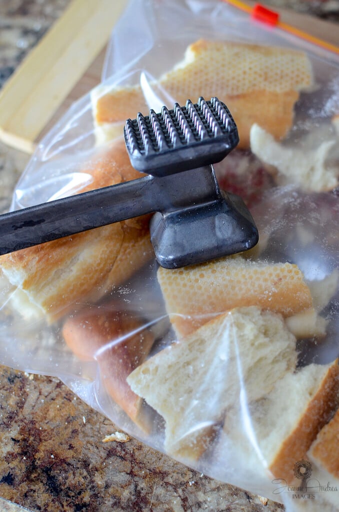 Pieces of dried baguette in a bag with a mallet about to crush the bread