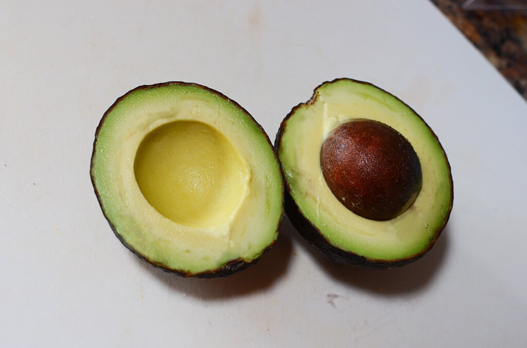 A perfectly ripe, cut avocado on a cutting board.