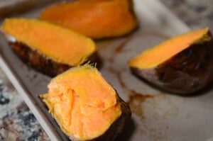 The cooked sweet potatoes are halved and ready to be scooped out, making them into little boats.