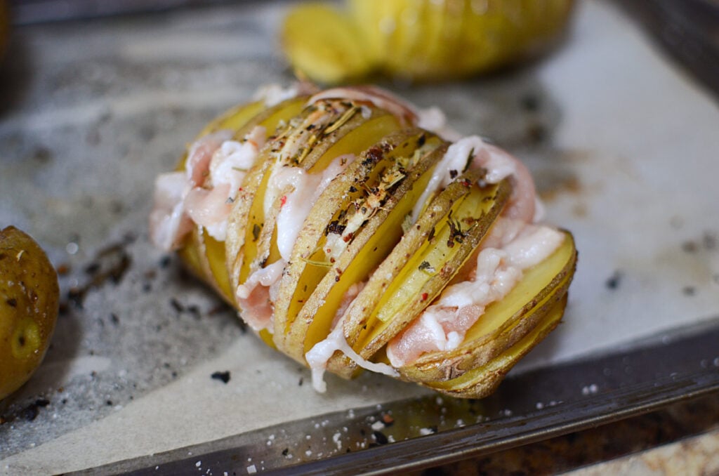 Sliced potato with bacon and onion, read to go in the oven.