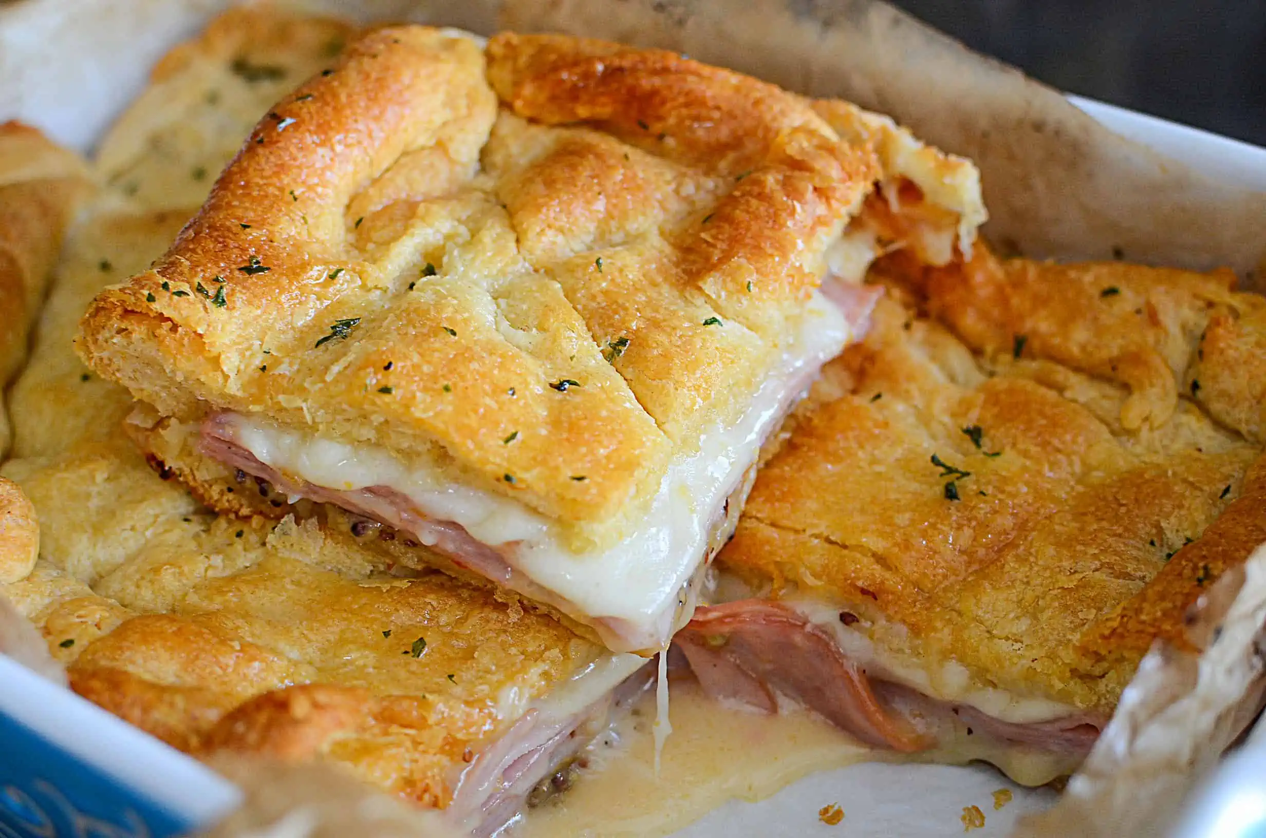 A hot ham and cheese sandwich fresh from the oven, laying on top of the other sandwiches.