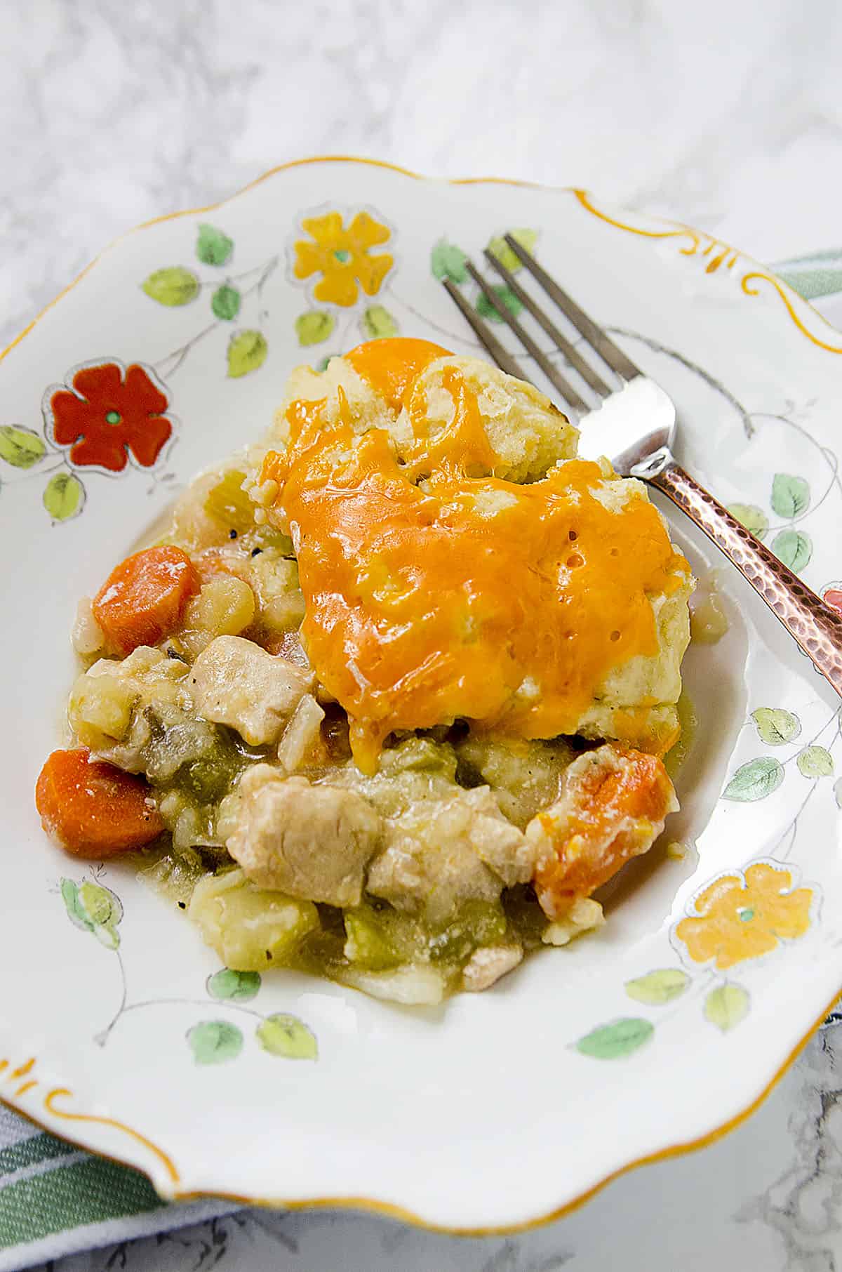 Chicken stew in a flowered plate with a fork on the right hand side.
