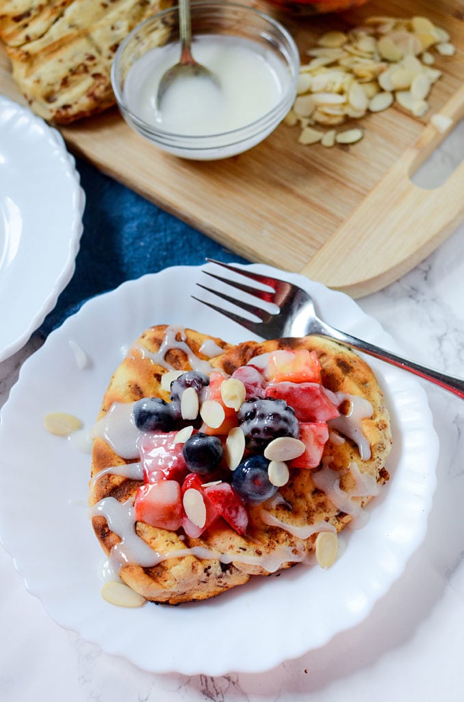 Fruit topped cinnamon flatbread on a white plate with a fork on the right.