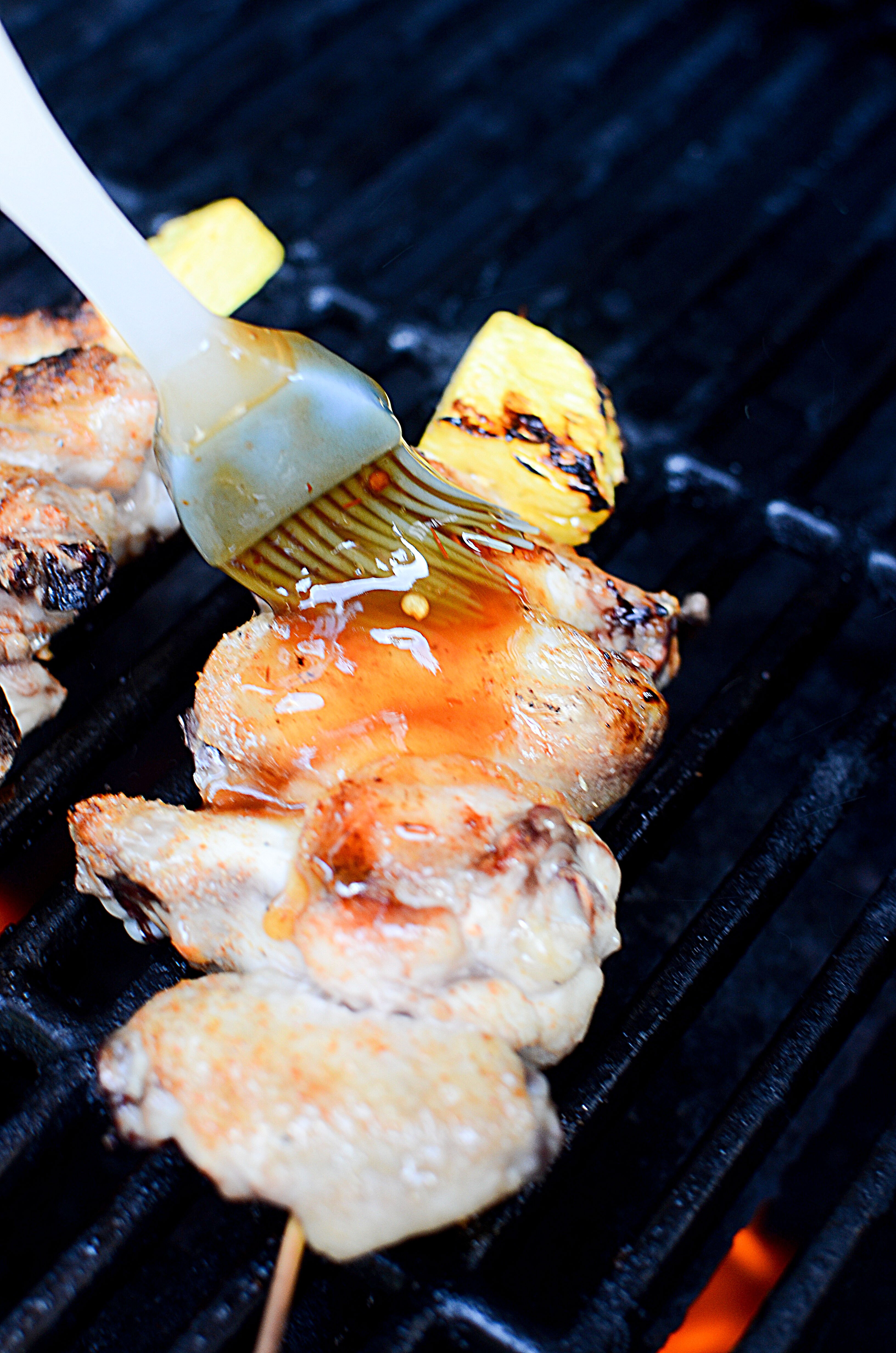 Basting the cooked wings on the grill.