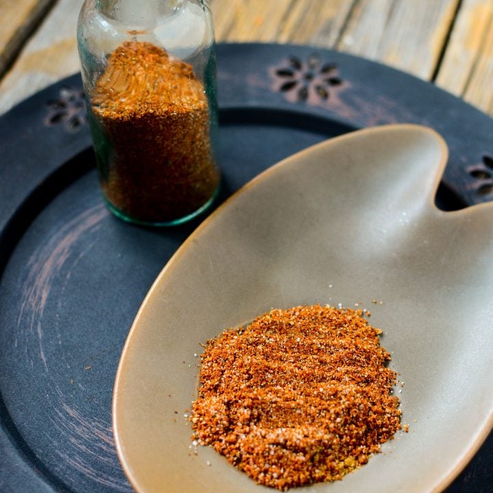 This taco seasoning is so pretty on the little brown plate with a bottle of the seasoning beside it.