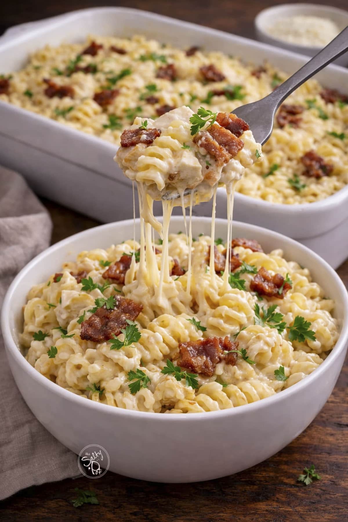 cheesy chicken pasta in a bowl with a fork taking a bite.