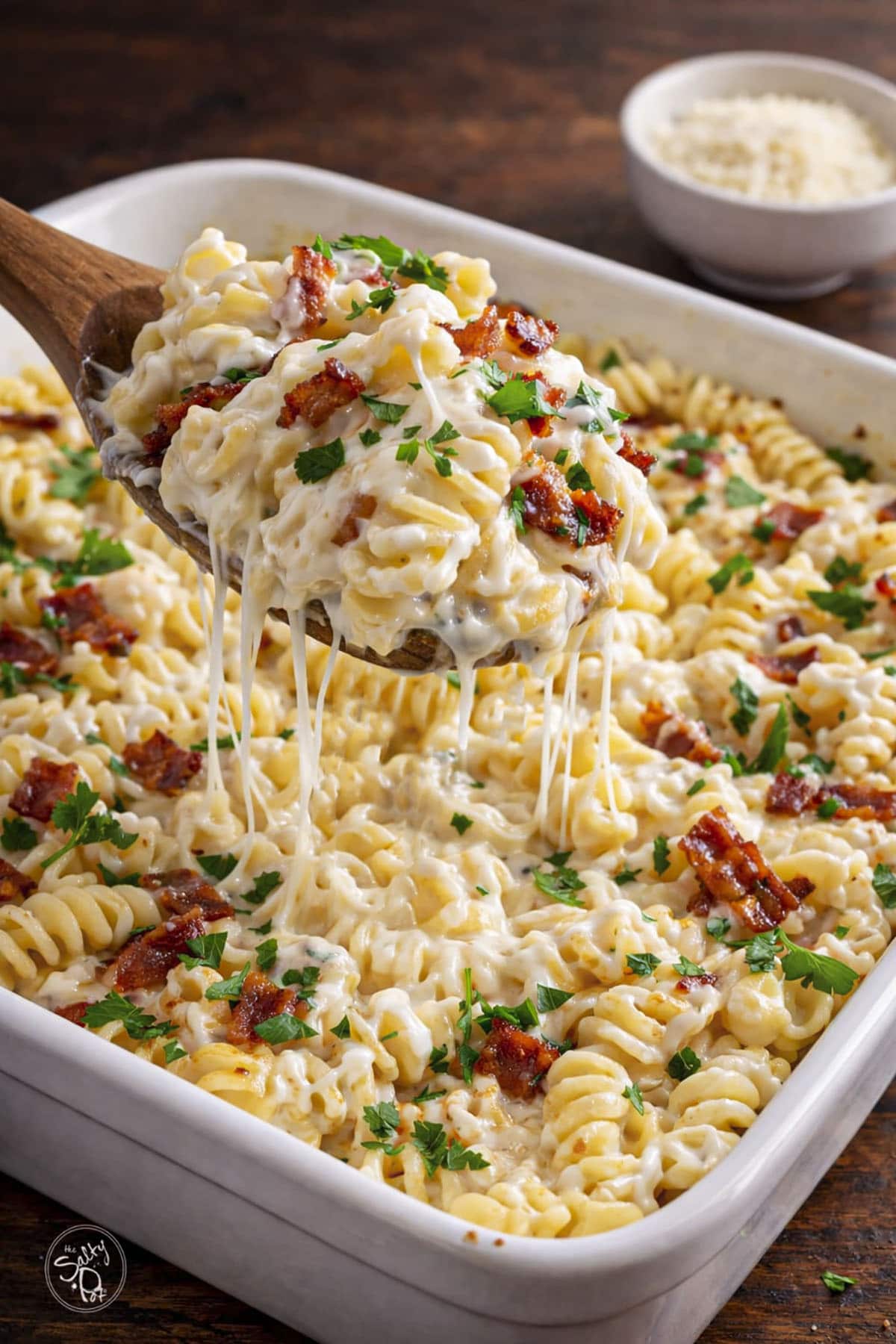 Chicken pasta casserole in a baking dish with a spoon lift shot.