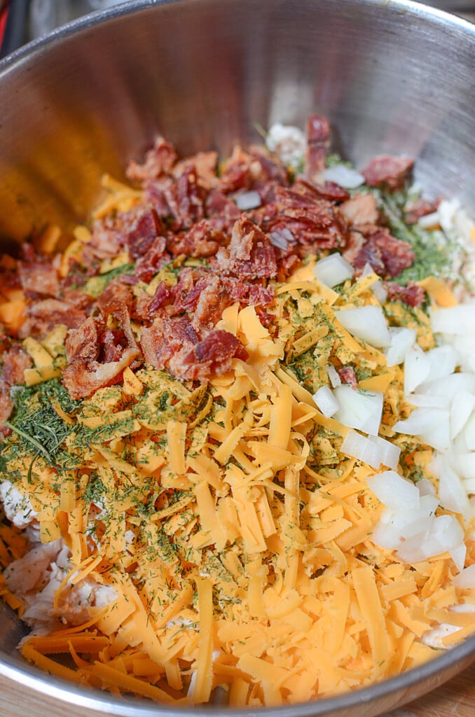 Bacon, cheddar, onions and spices in a silver bowl ready to be mixed with the chicken and potatoes.