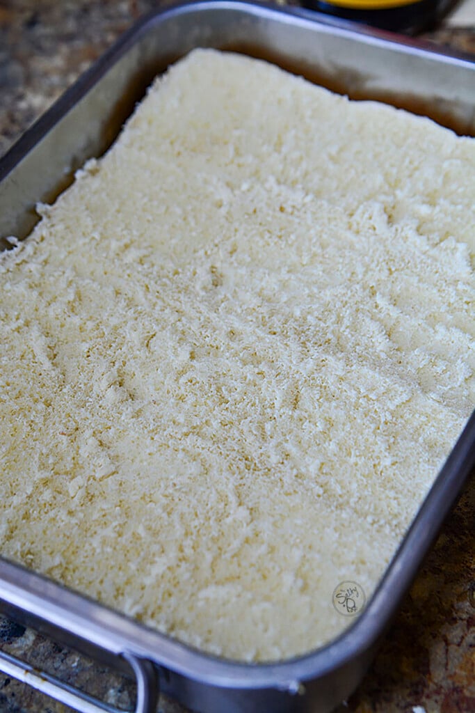 The bottom half of tray buns in a silver baking tray.