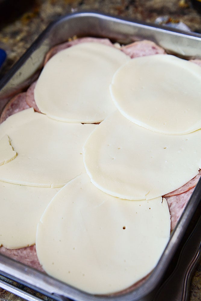 Slices of provolone are placed on top of the deli meats for these sliders.
