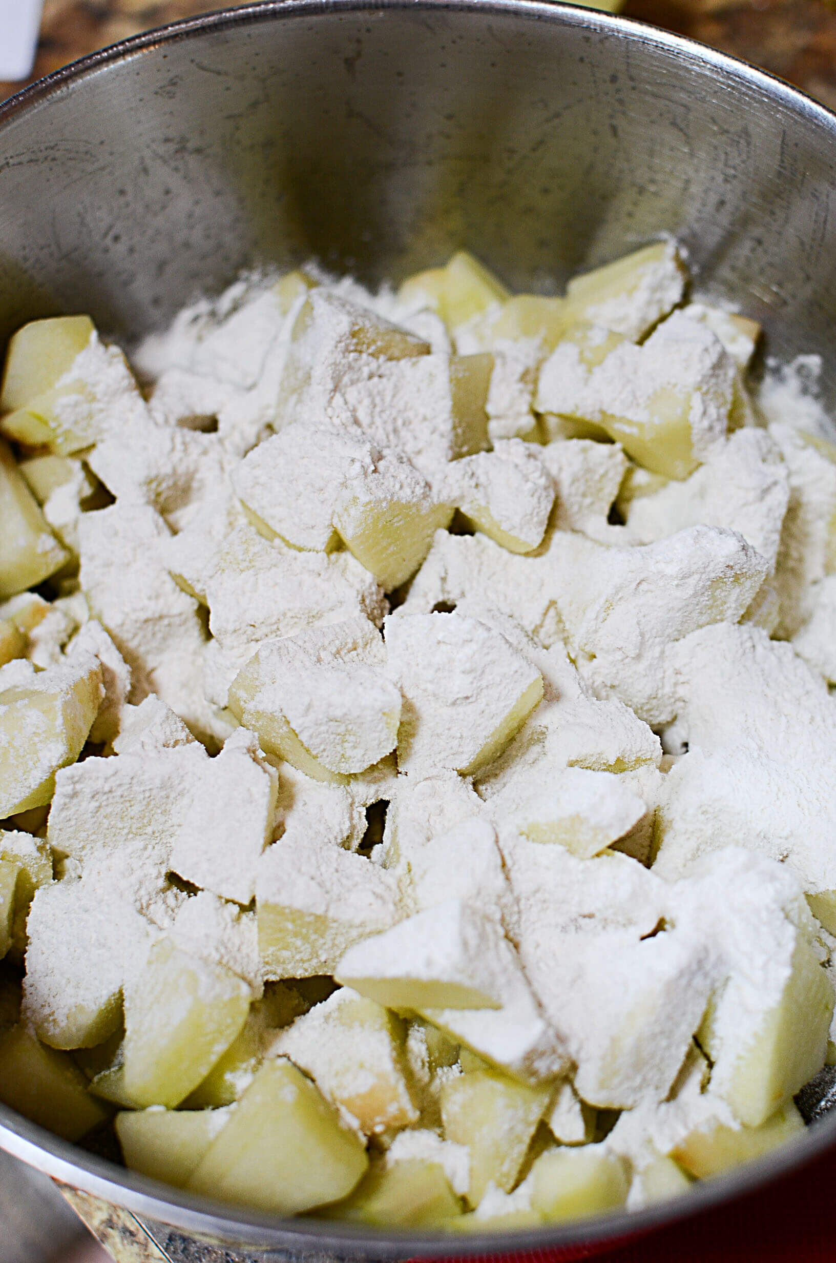 A bowl holding the diced apples with some flour sprinkled on top.