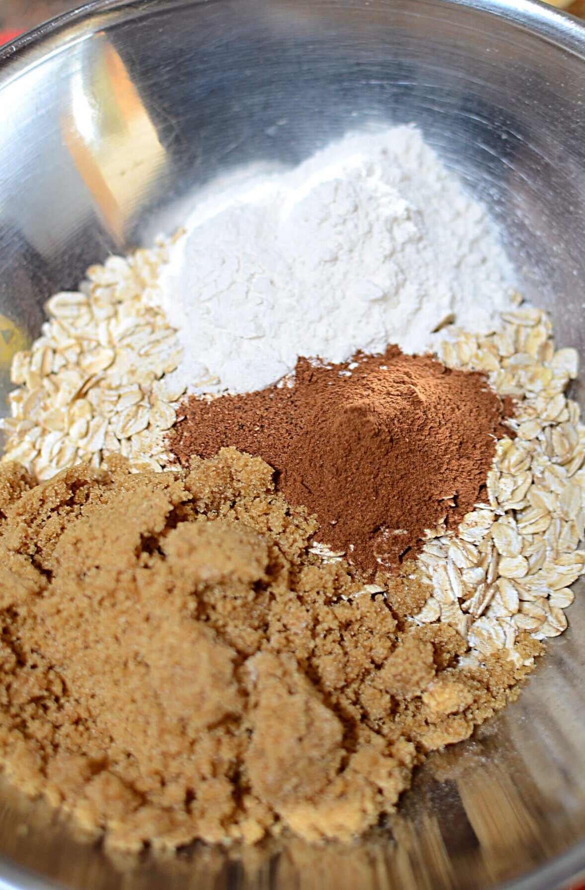 The topping ingredients in a silver bowl. Oats, flour, cinnamon, nutmeg and brown sugar.