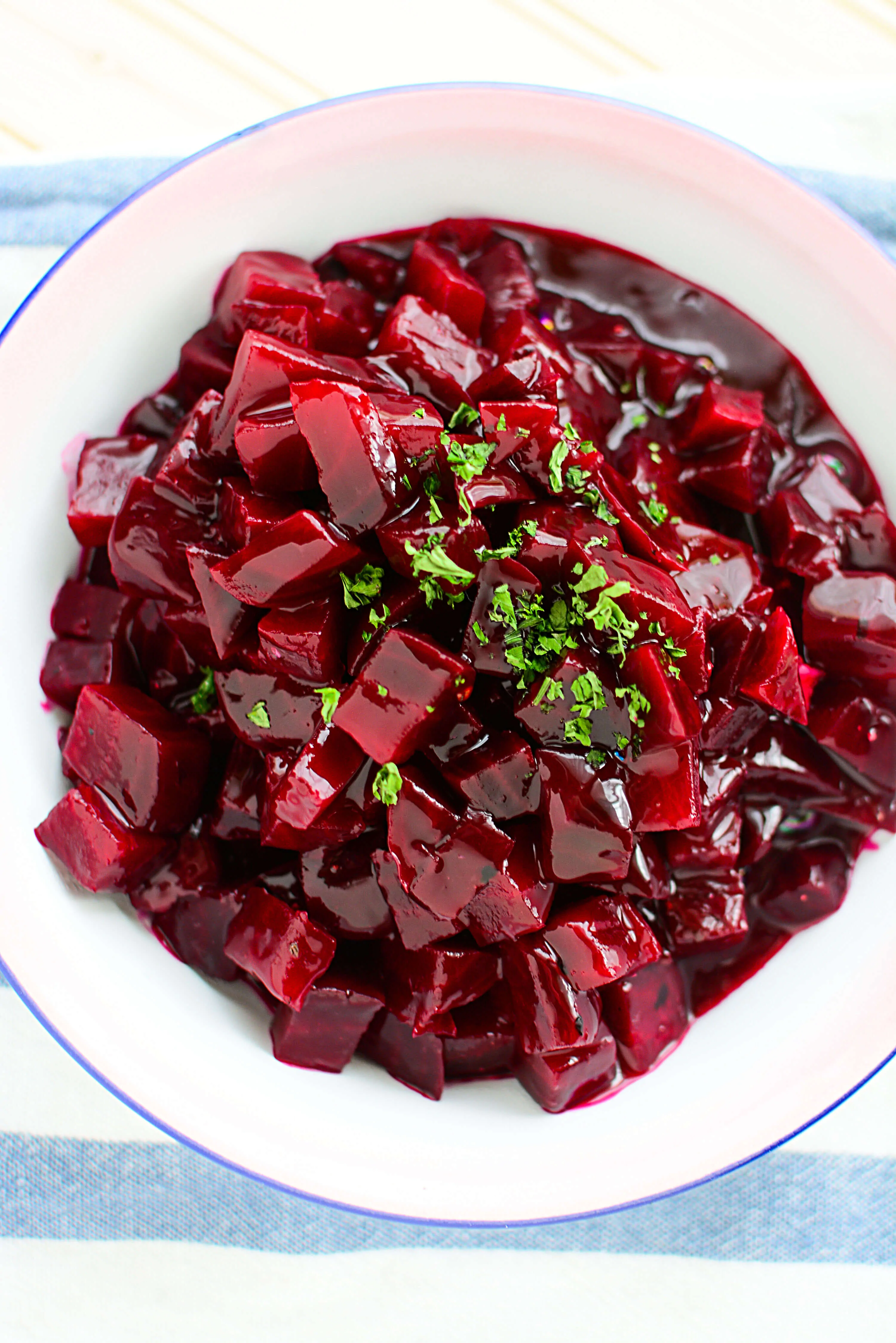 A bowl of harvard beets in a blue and white napkin.