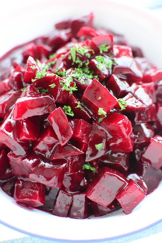A close up photo of harvard beets sitting in a white enamel bowl.
