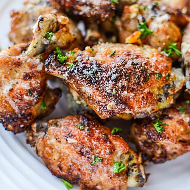 Garlic Parmesan Wings piled on a white plate with parsley.