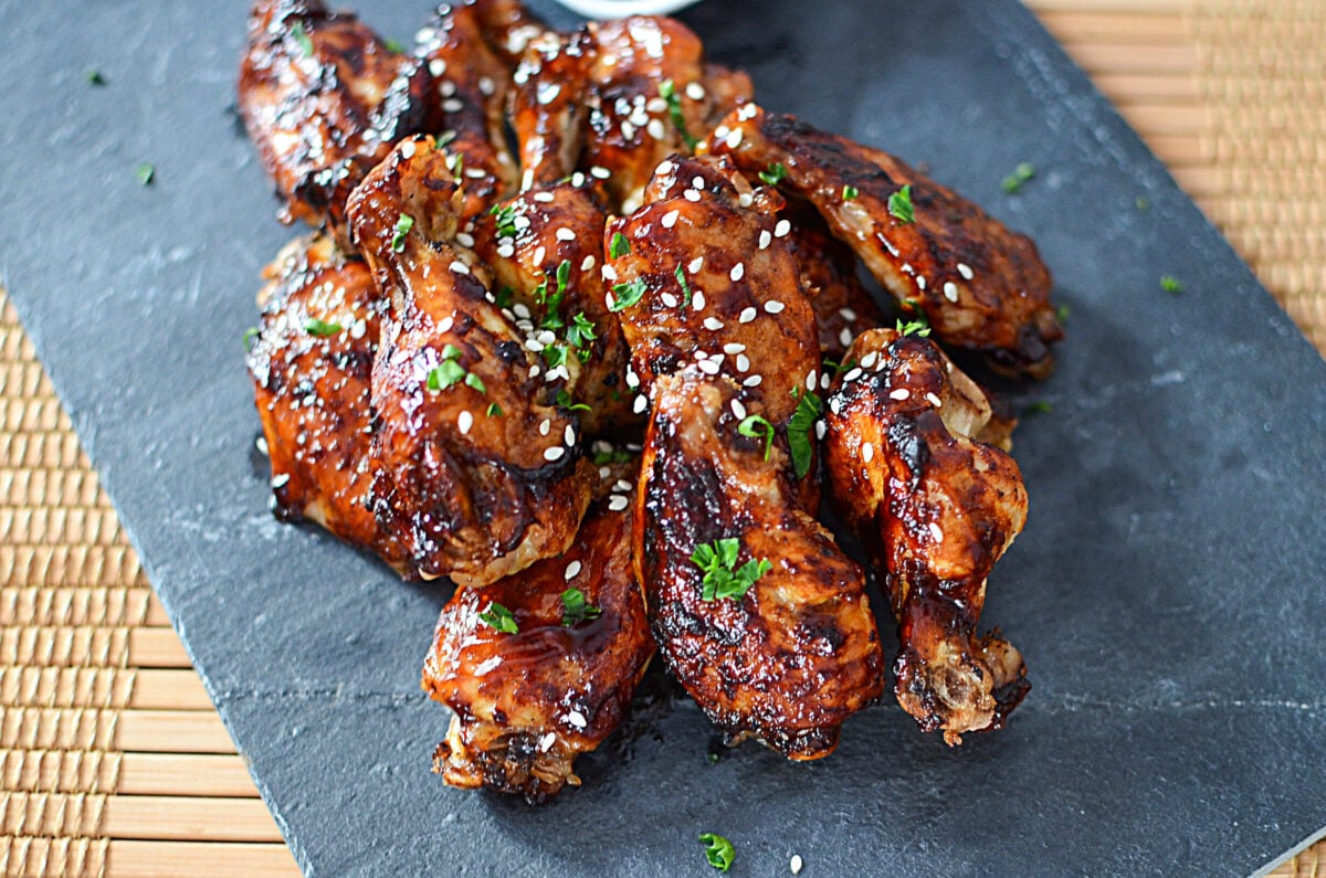 Ninja Foodi Teriyaki wings on a slate board with sesame seeds sprinkled on top.