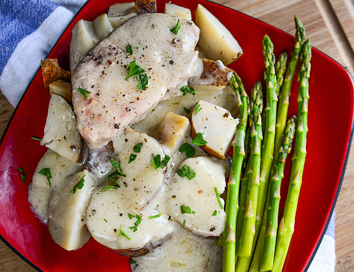 Ranch pork chops with asparagus on a red plate.