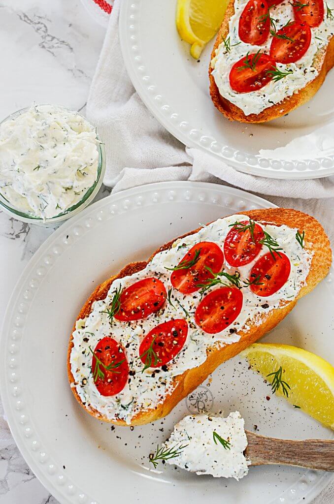 The lemon dill yogurt spread on toasted bread with cherry tomatoes on top and seasonings. 