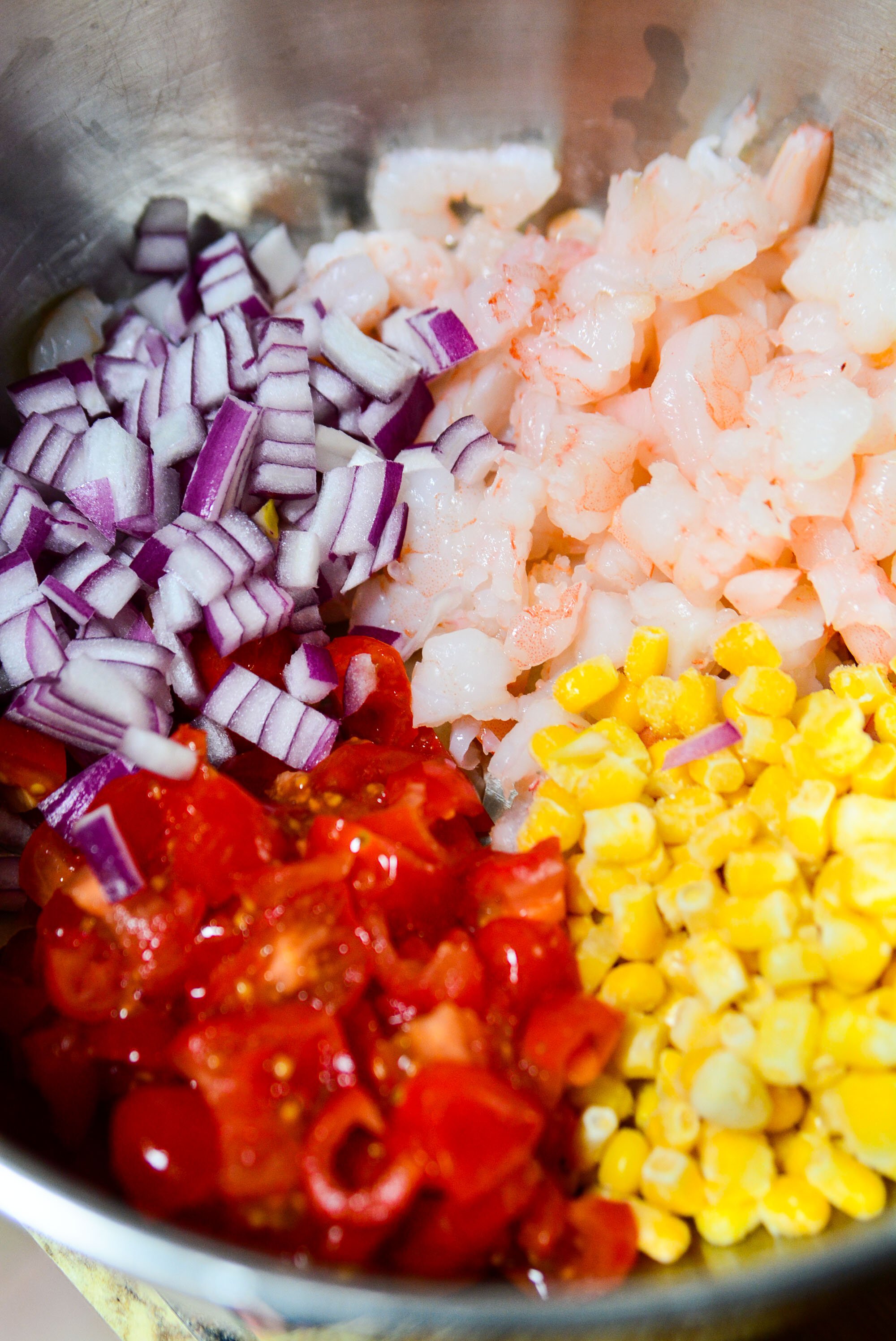 Clockwise, Chopped shrimp, corn, red chopped tomato, and purple onion.