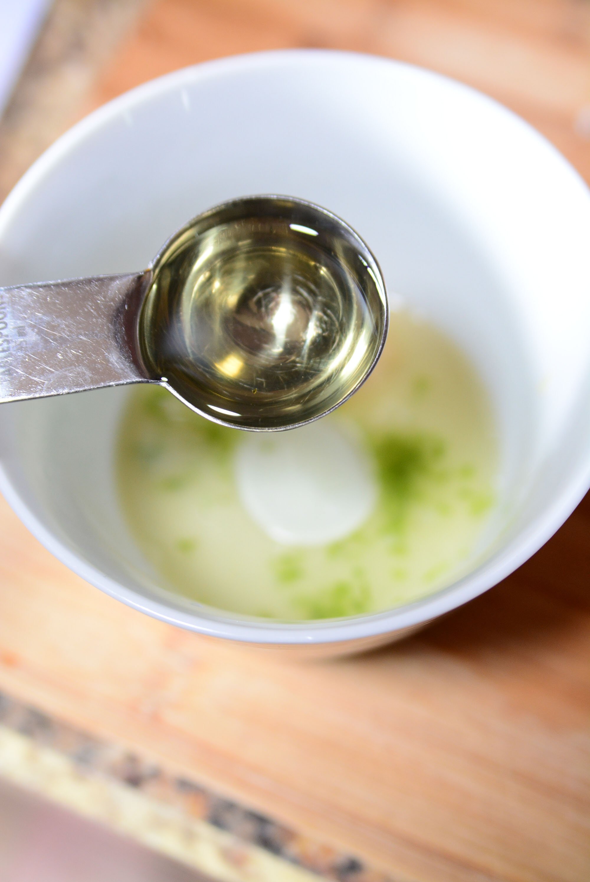 Making the dressing in a white bowl with lime juice in the bottom.