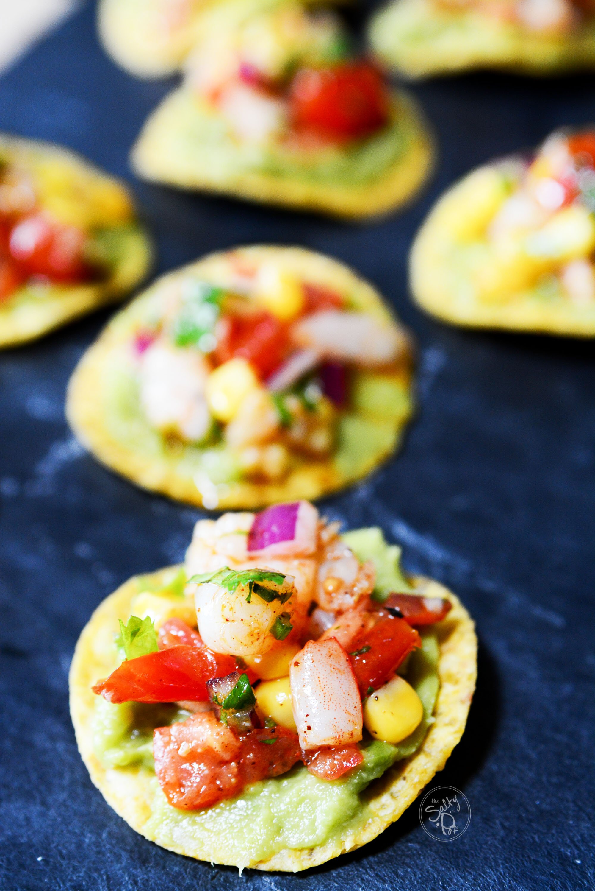 Shrimp, corn, tomato and avocado filling on a tortilla chip.