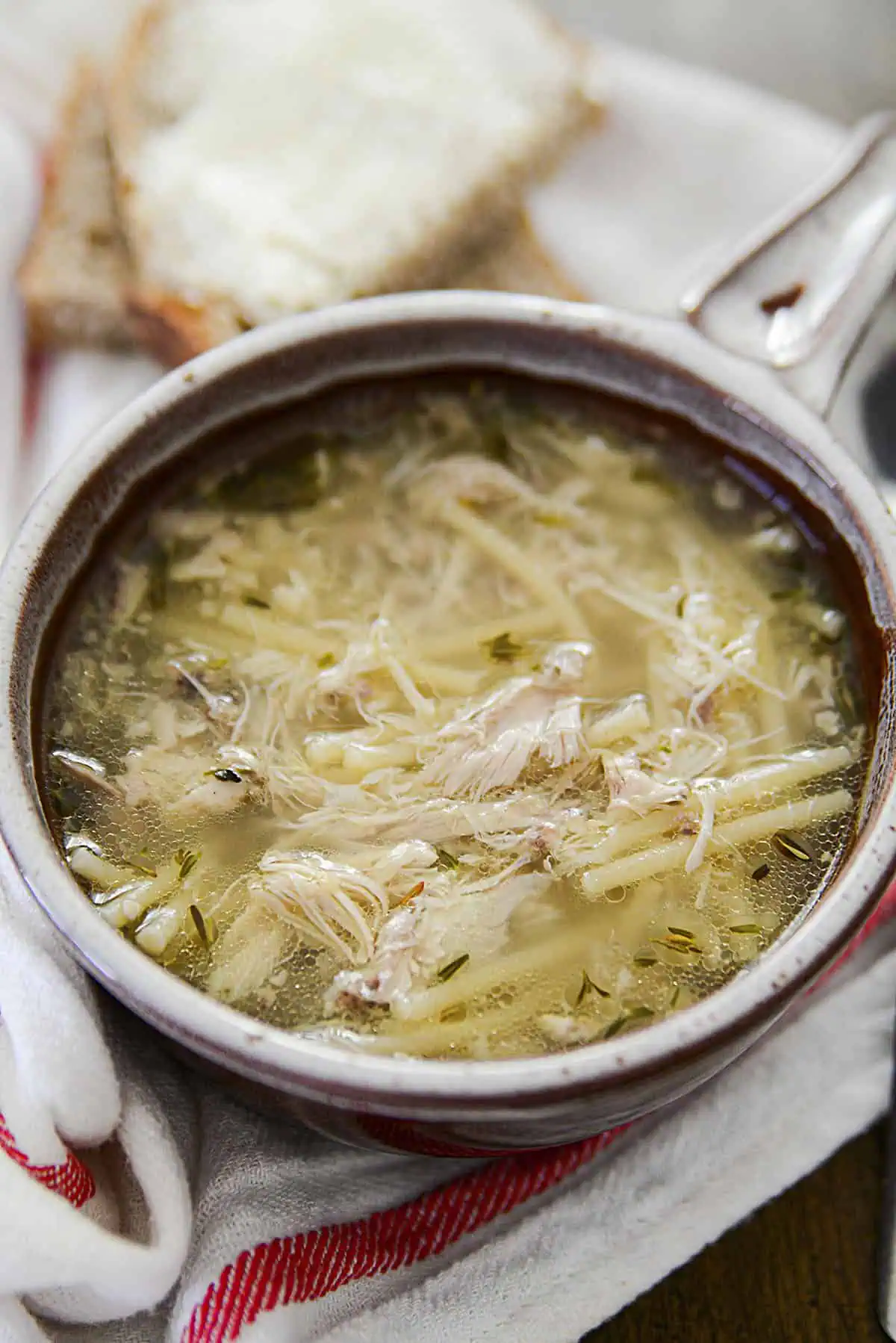 Chicken noodle soup in a pottery dish.