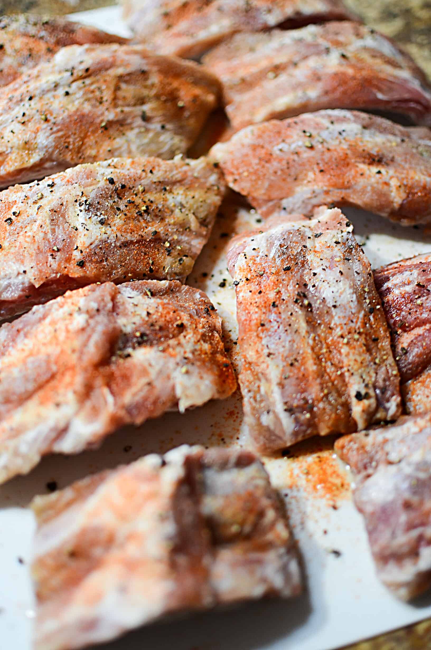 Uncooked ribs sprinkled with seasonings.