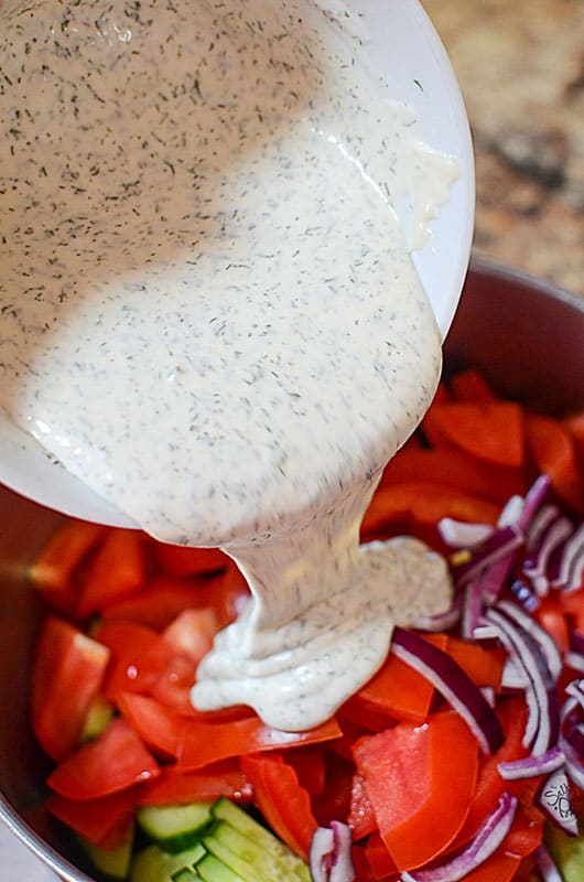 Dill dressing being poured on top of the fresh vegetables