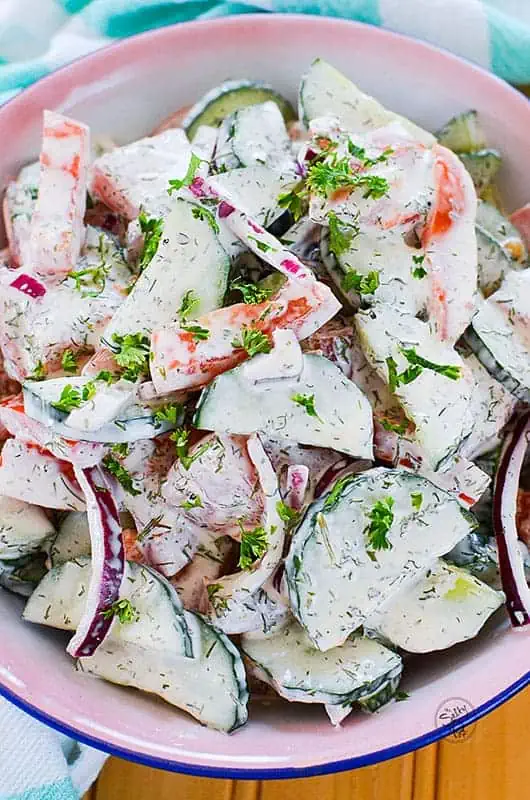 Creamy cucumber tomato salad - fresh cucumber and tomatoes with red onions in a bowl with dressing