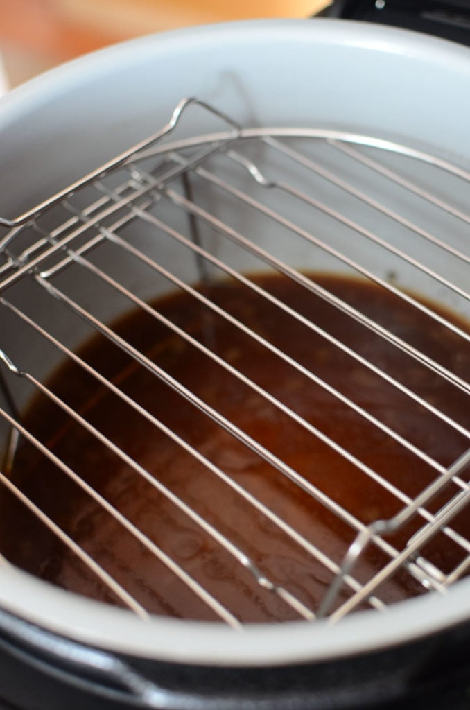 The air crisping rack of the ninja foodi inside the pot with cooking liquids at the bottom