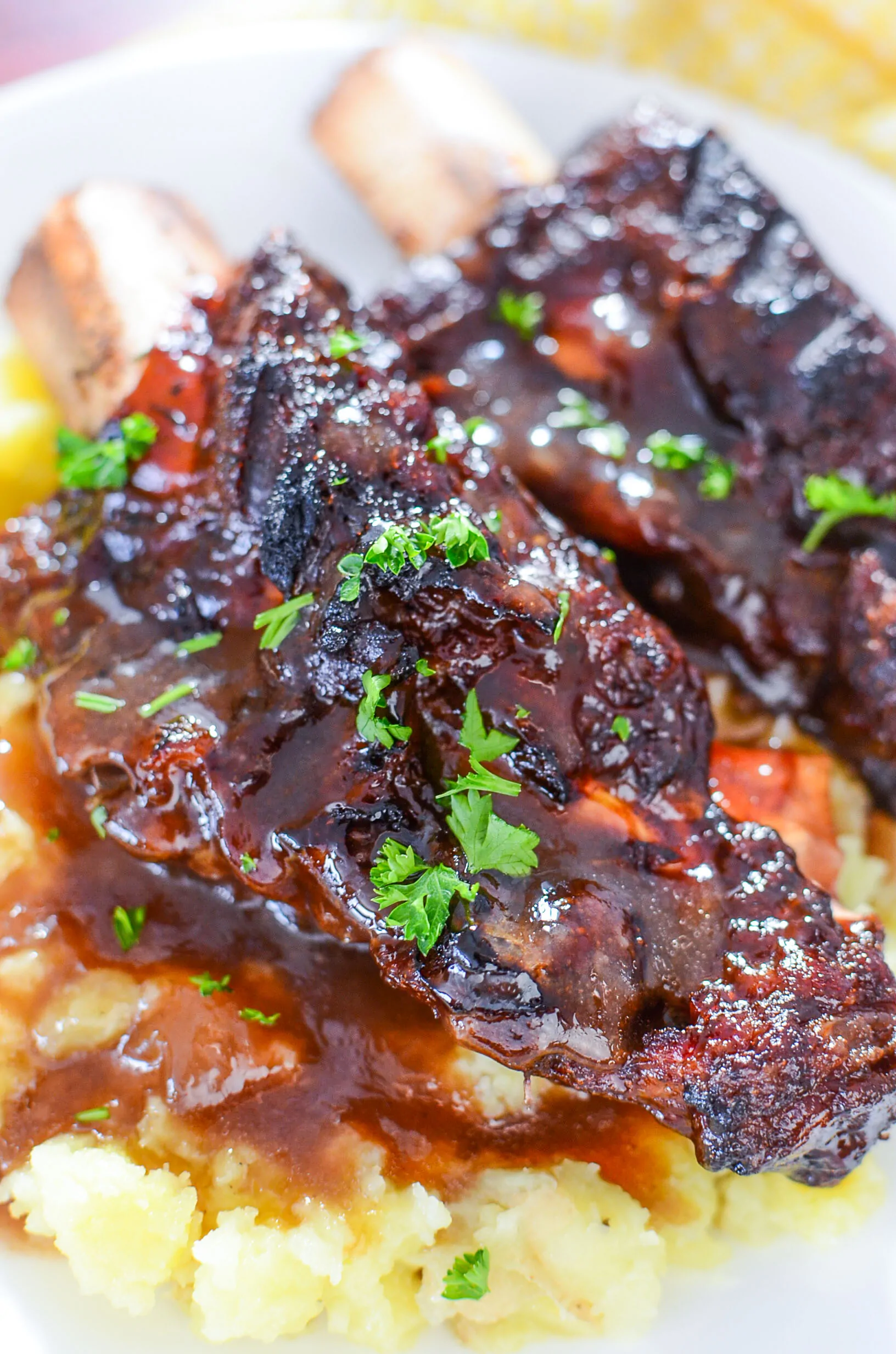 Two beef ribs on mashed potatoes with gravy over top.