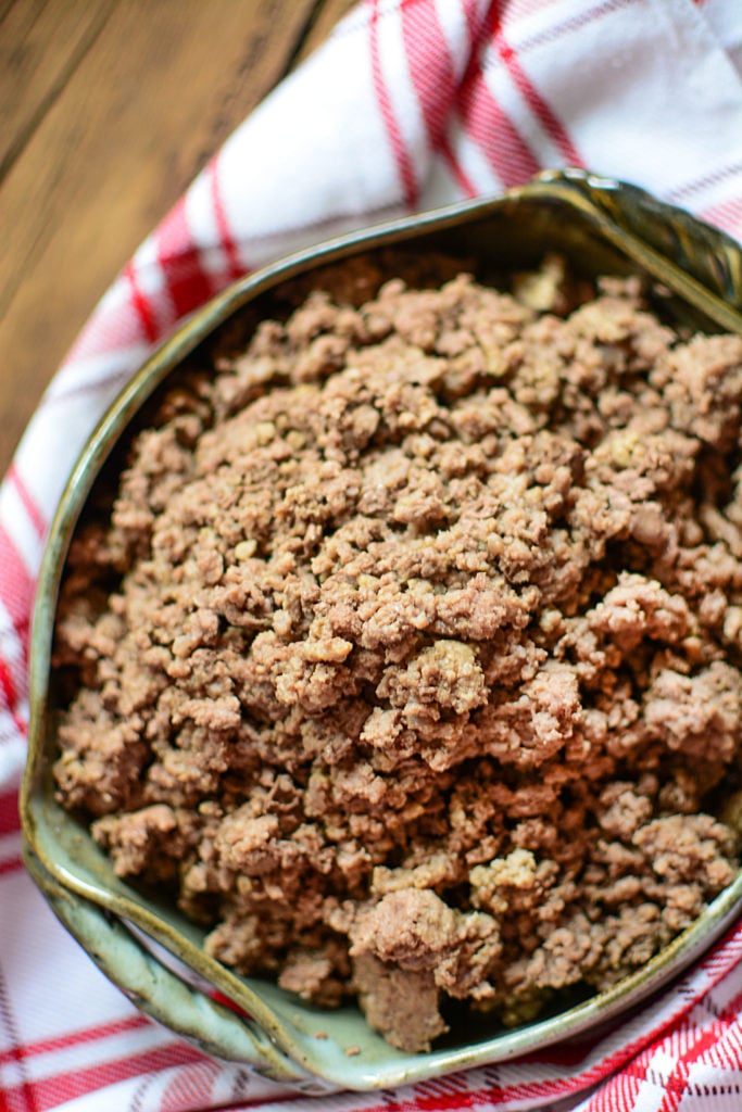 Cooked ground beef in a green pottery dish on a red napkin