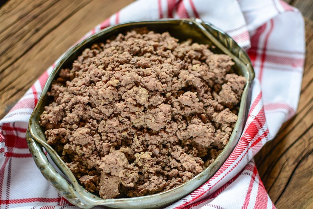 beef mince, cooked, in a green pottery serving dish on a red napkin