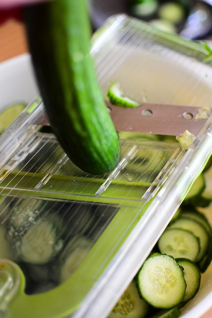 slicing the cucumbers on a mandoline