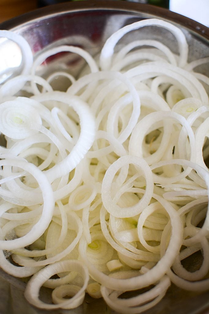 Sliced onions in a bowl, getting ready to join the cucumbers to make pickles