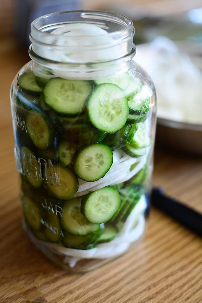 cucumbers and onions packed into a mason jar, waiting for the brine