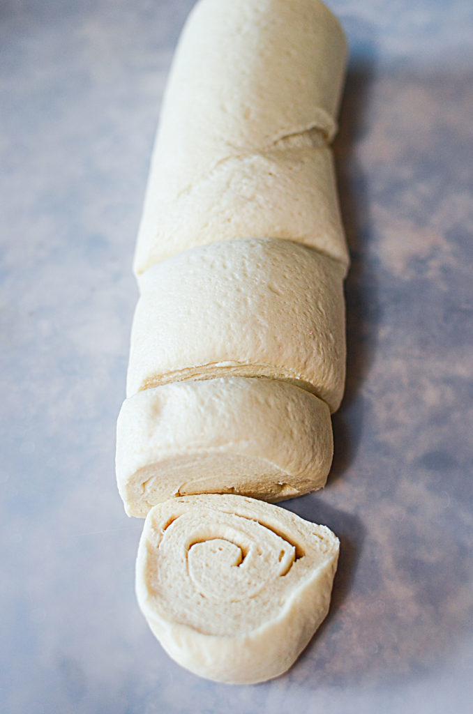 The pizza dough rolled up with one cut from it