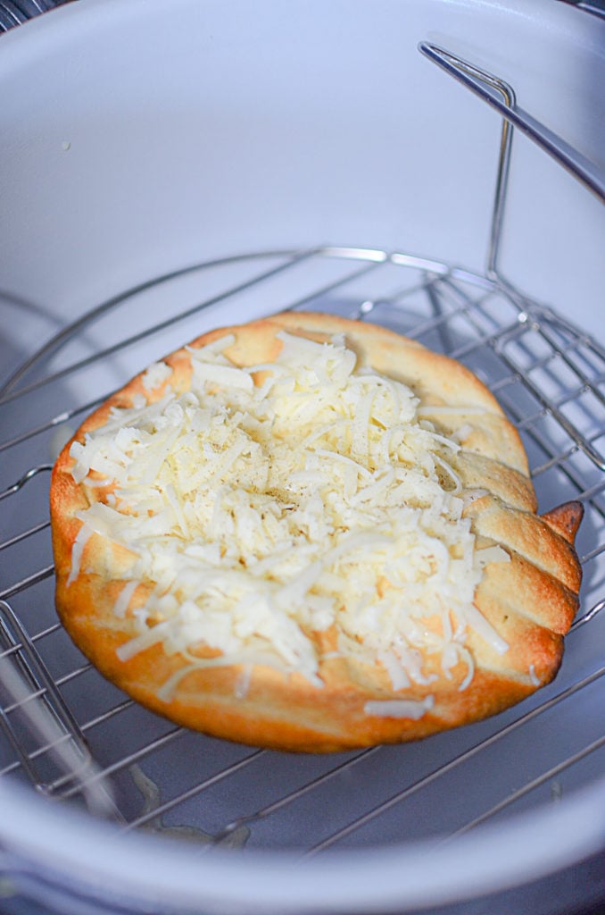 A picture of the bread on a rack inside the ninja foodi with cheese on it