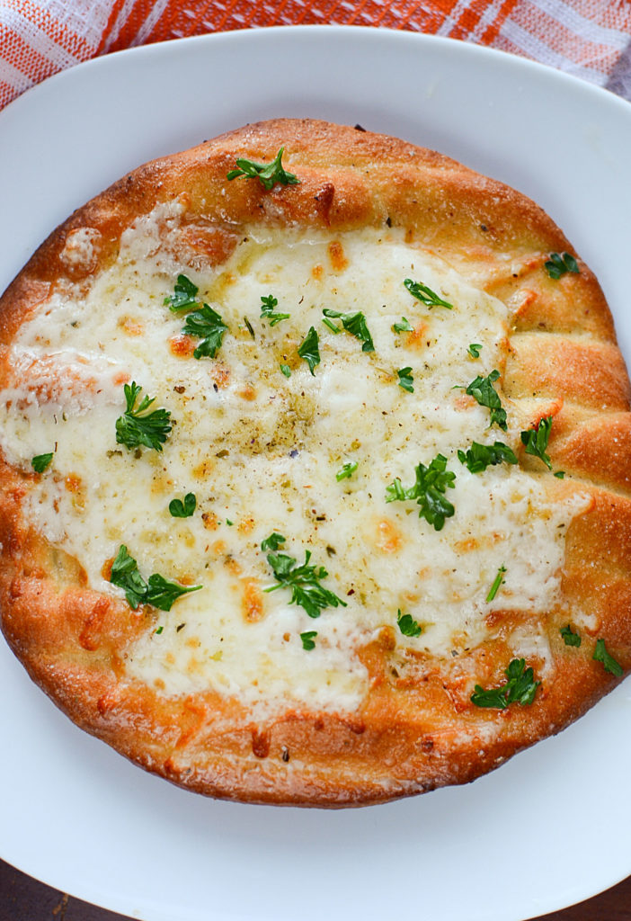 Beautiful, golden brown air fried cheesy flatbread made in the ninja foodi served on a white plate.