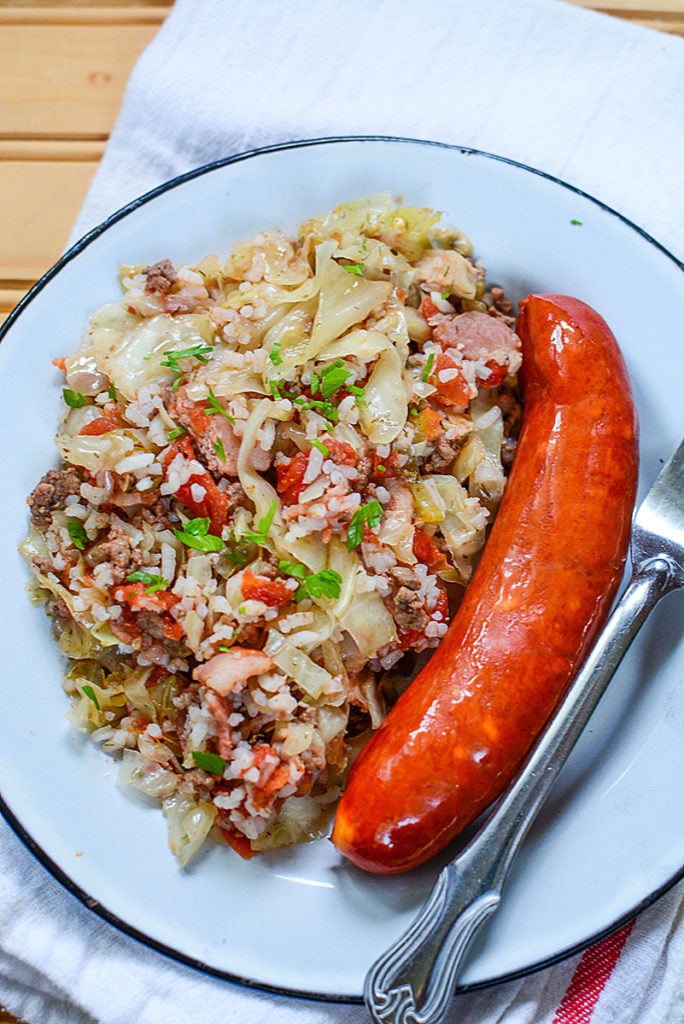 Another close up of the lazy cabbage rolls on a white plate with sausage beside it