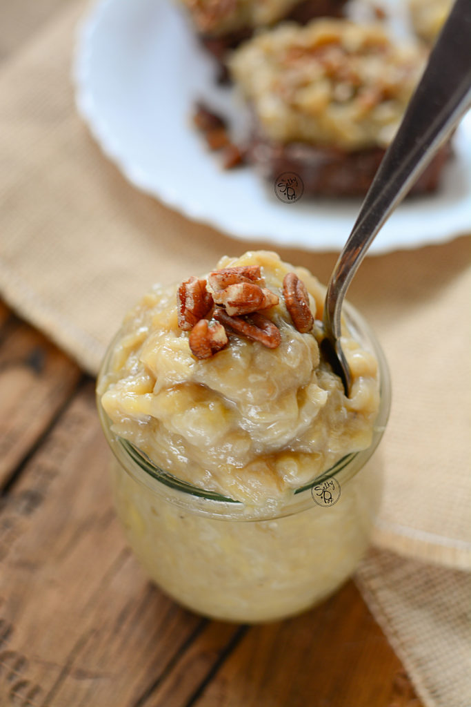 Instant pot Banana butter in a jar, piled high with pecans on top and bread in the background