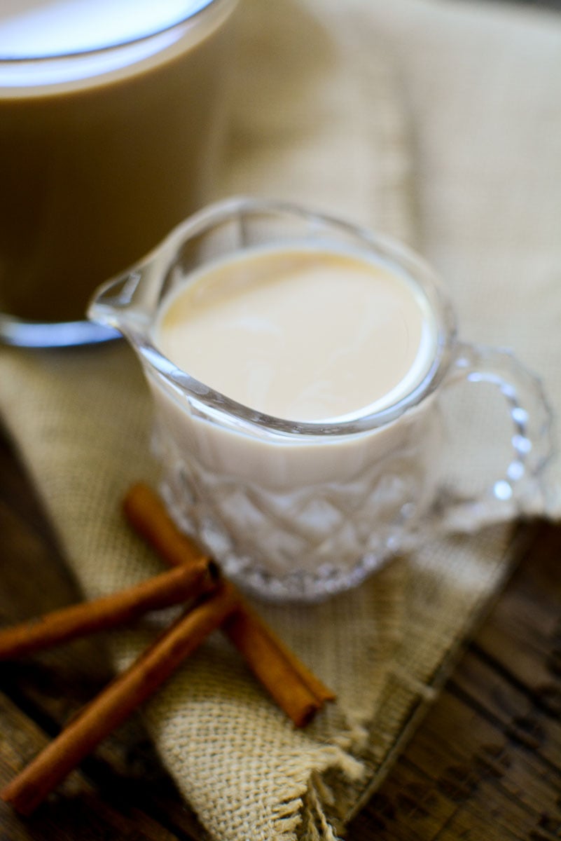 A small glass creamer jar holding cinnamon flavored coffee creamer.