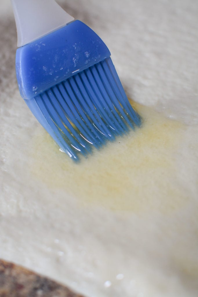 Brushing the dough with butter.