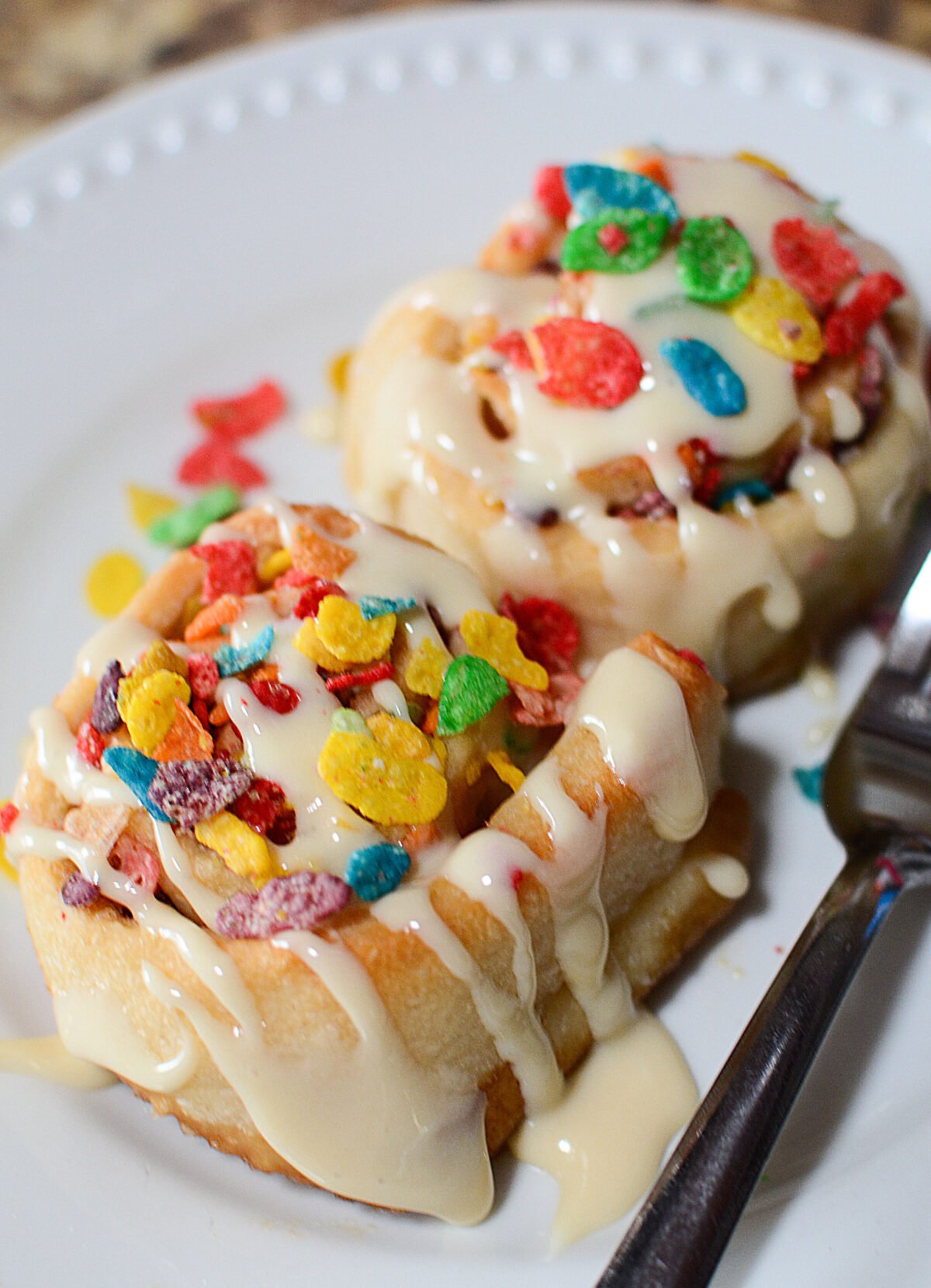 Fruity pebbles sweet rolls on a white plate.