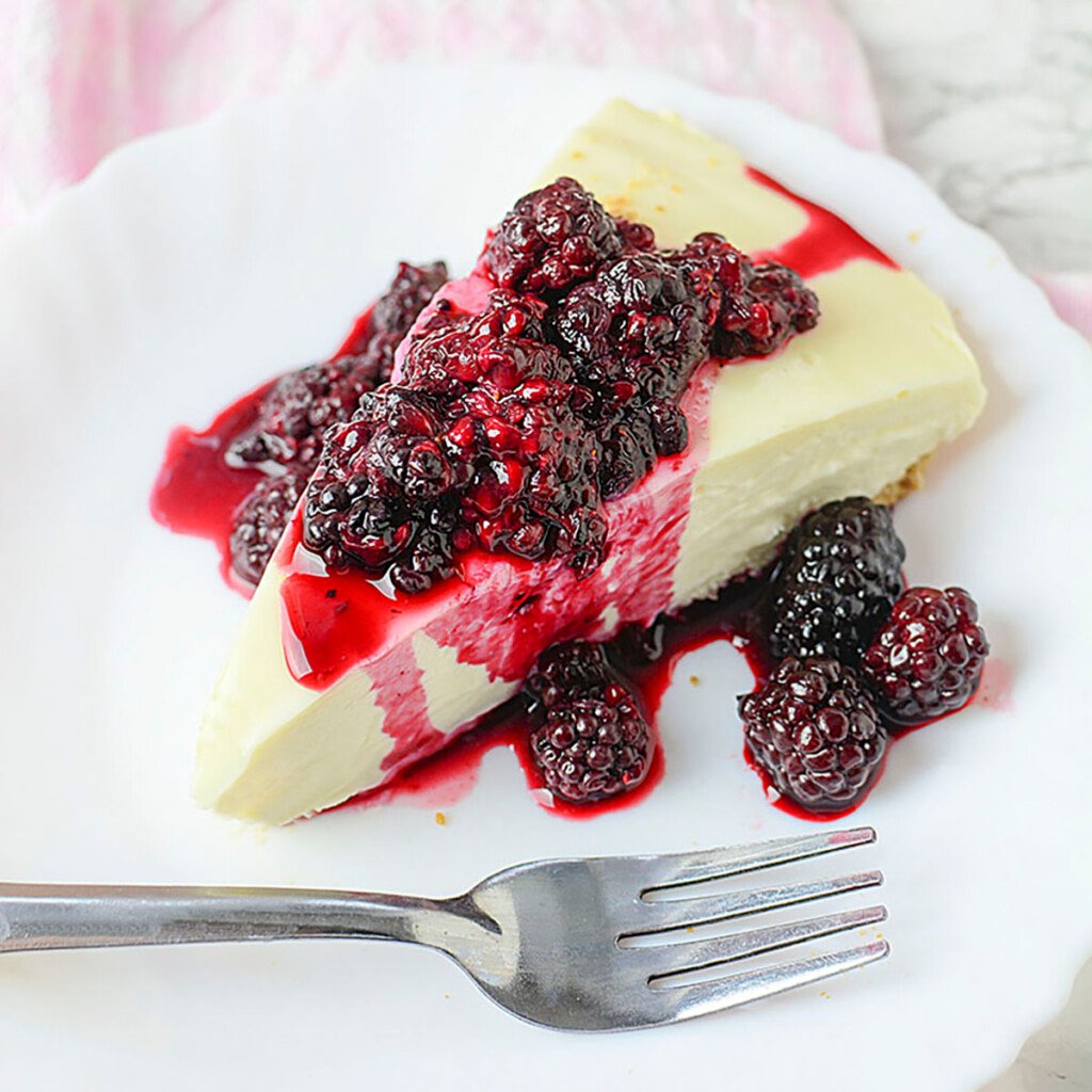 3 Ingredient cheesecake with blackberry topping on a white plate with a fork.