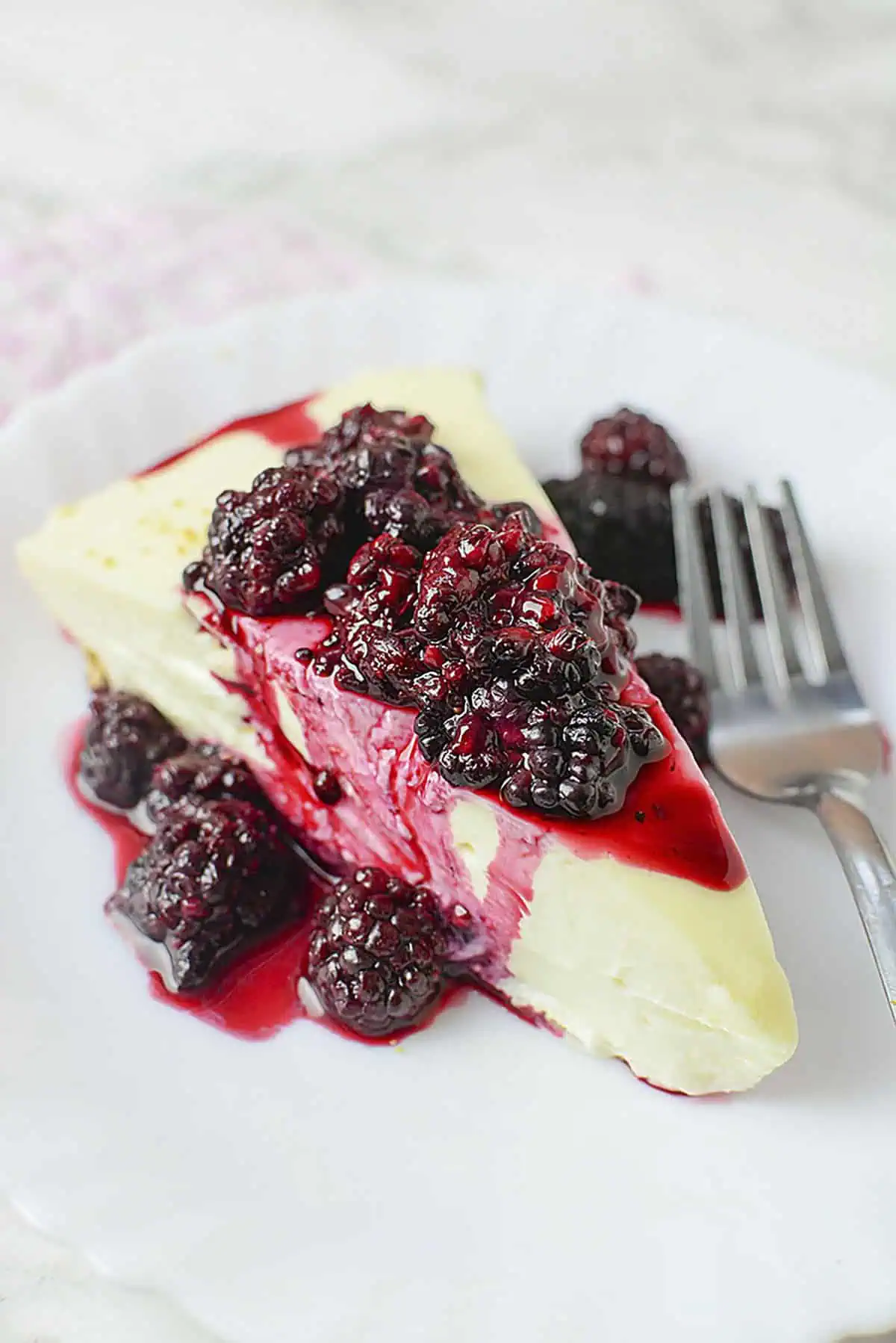 A slice of 3 ingredient no bake cheesecake on a white plate.