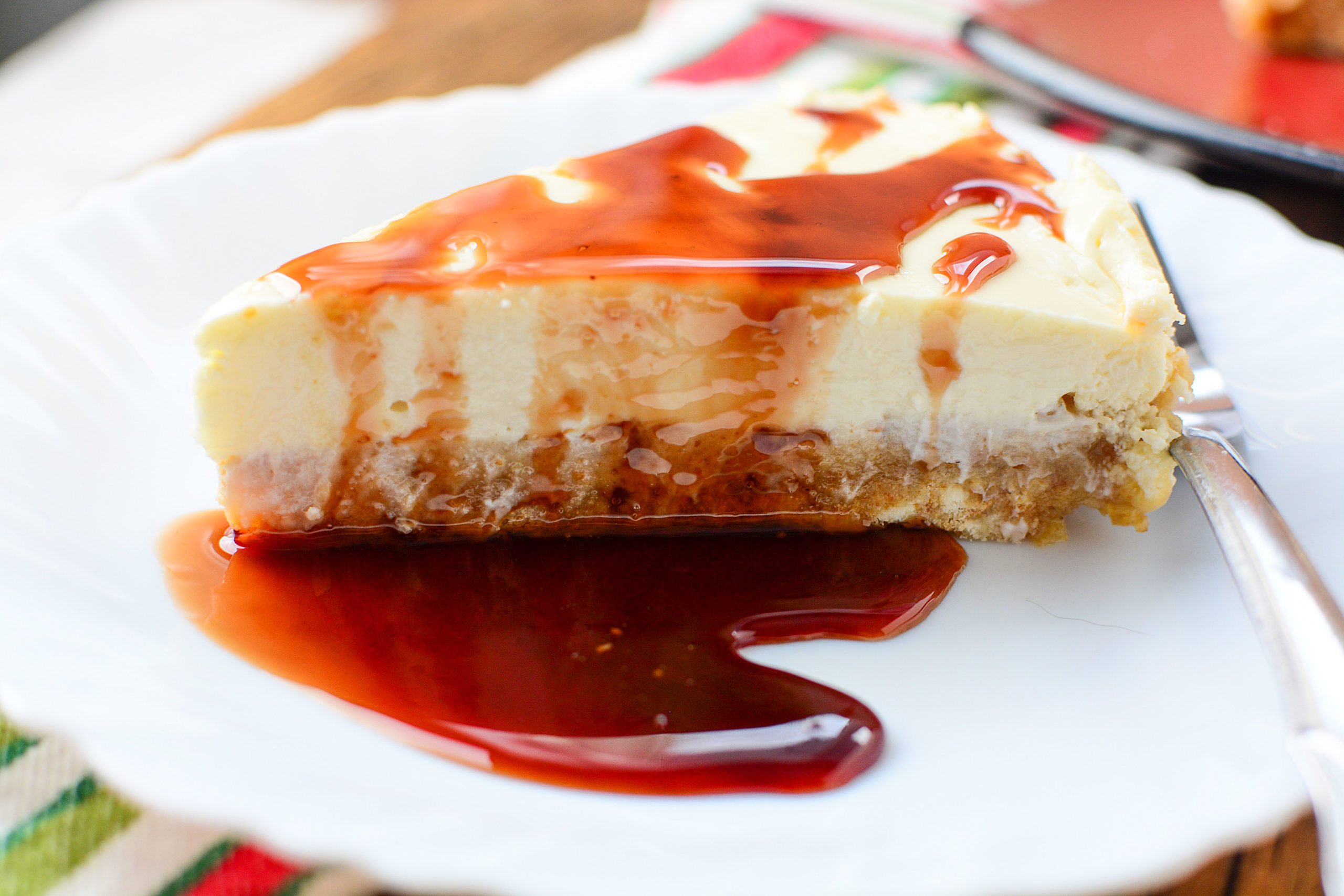 A slice of cheesecake with pomegranate sauce over top.