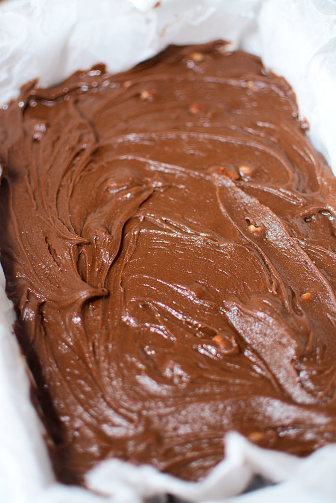 en blanding av peanøttsmør og sjokoladefrosting med noen pekannøtter lagt ut på en bakepanne med bakeplate